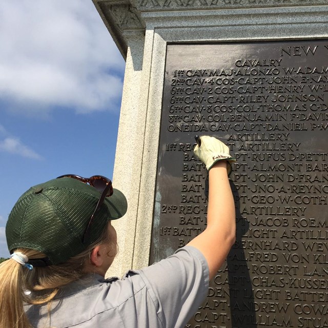 Park staff working on bronze feature of a monument.