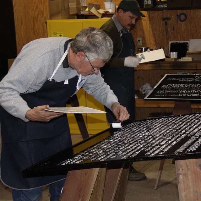 Park staff and volunteer working on tablet restoration.