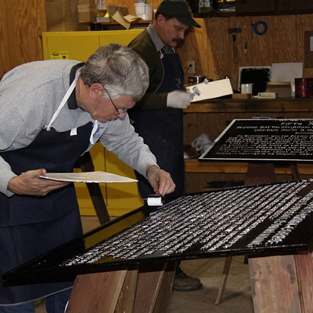 volunteer and nps employee painting a tablet