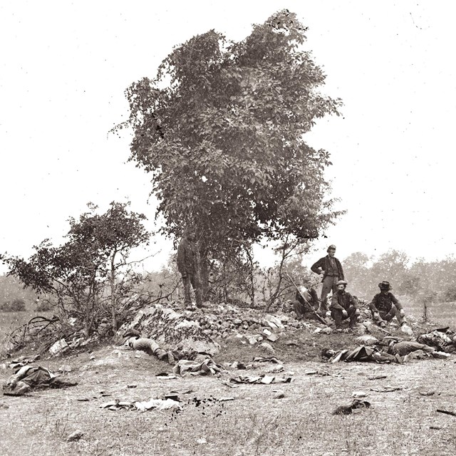 soldiers sitting on rock with battle debris in the foreground