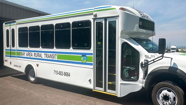 Photograph of white bus turning onto a snow-covered road.