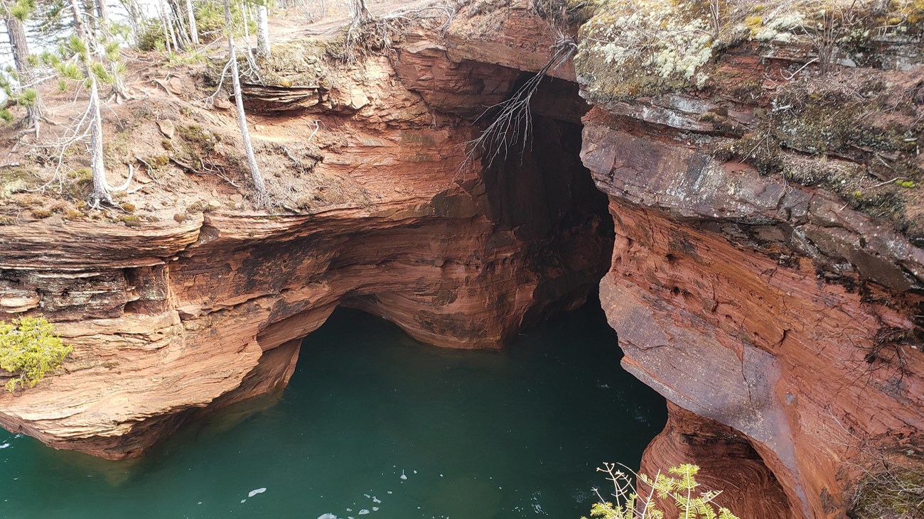 Orange sandstone cave over emerald green water.