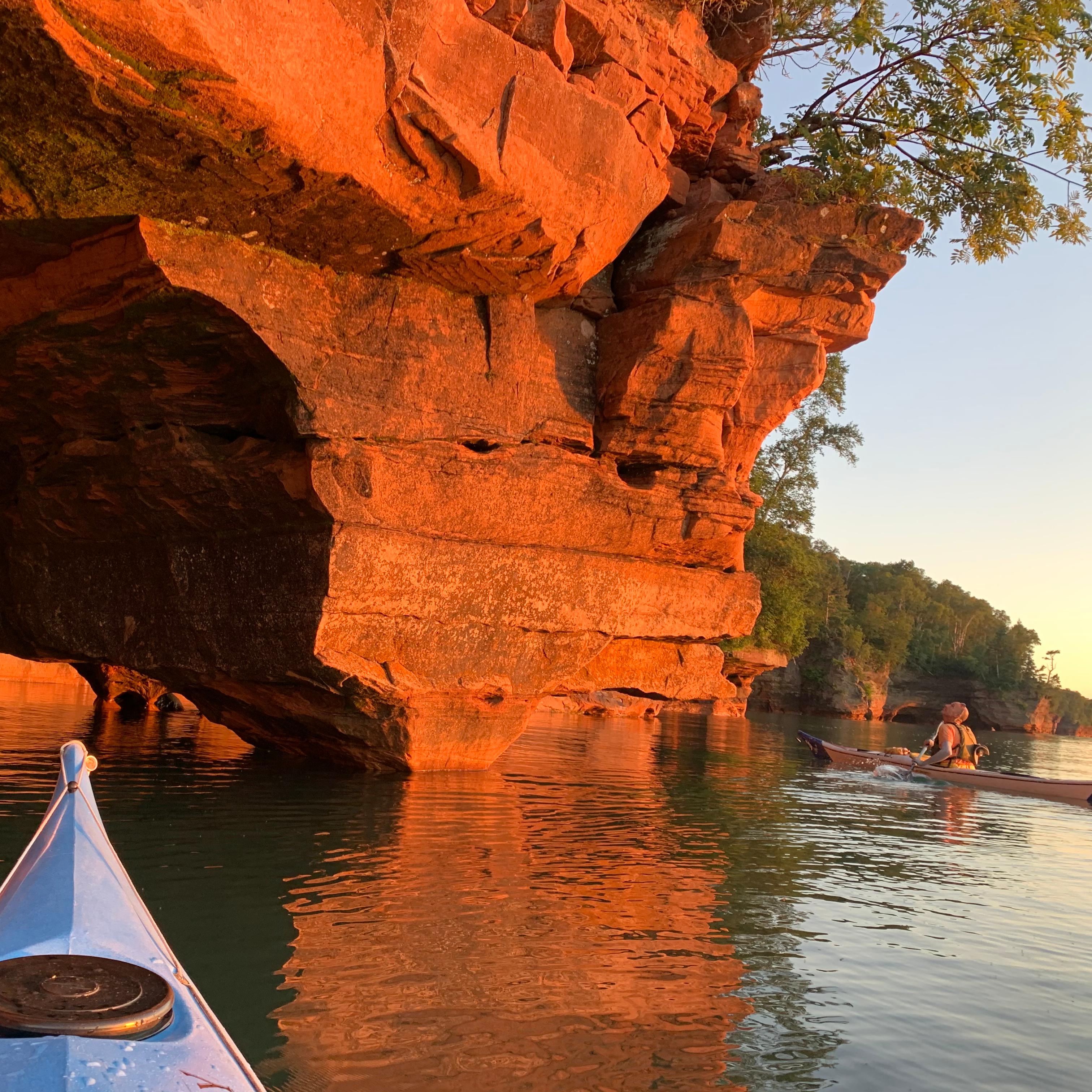 Kayaker looking up at a rock formation from the water. 