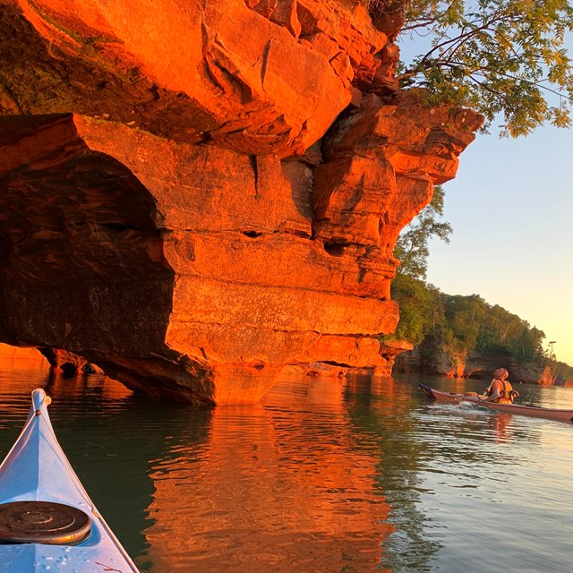 Kayaker looking up at a rock formation from the water. 