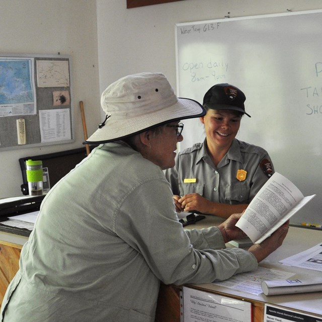 Visitor talking with ranger over desk.