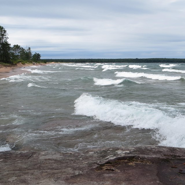 large white cap waves breaking near sandy beach during storm