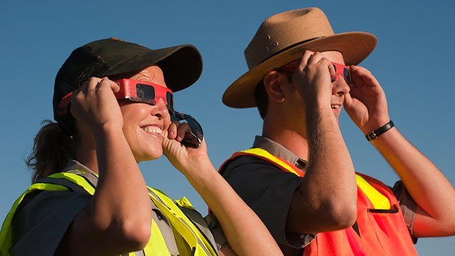 Rangers smile as they look through protective glasses at the Annular Eclipse.