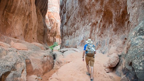a hiker walks between steep rock walls