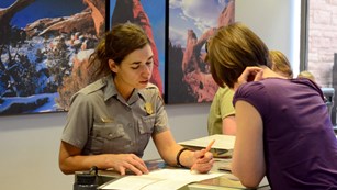 a ranger at an information desk points to a map