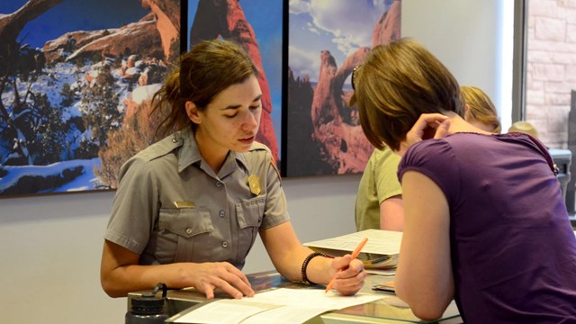 a ranger at an information desk points to a map