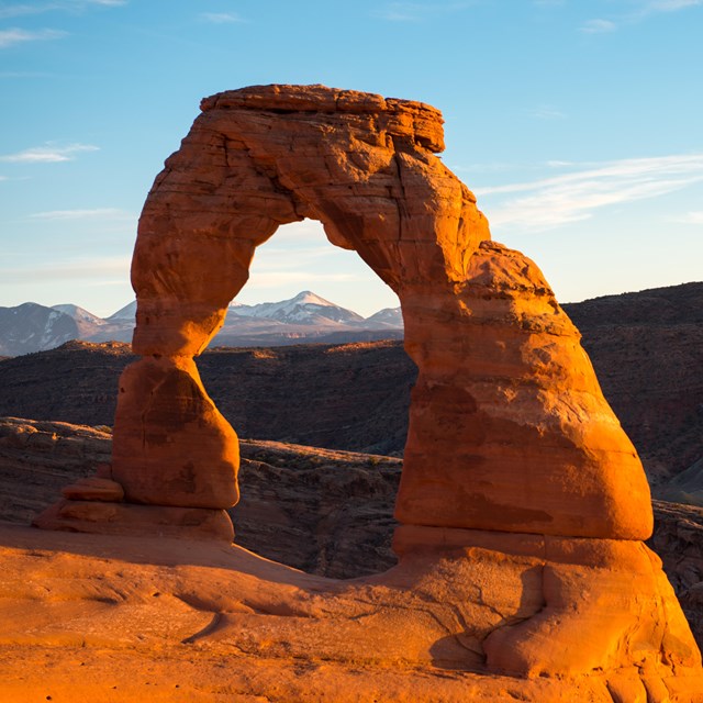 a red rock arch with snow-capped mountains in the background