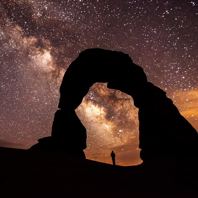 a silhouetted arch with the Milky Way arcing overhead
