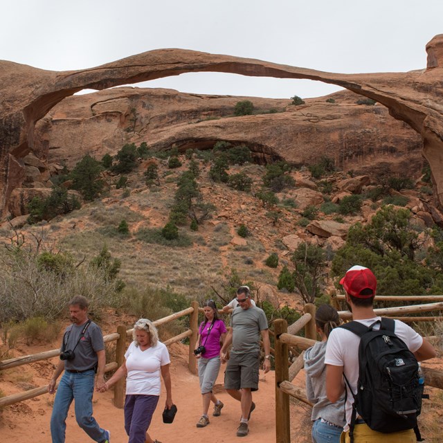 a group of people view a broad, thin arch