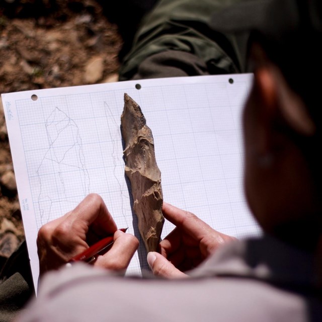 Spearpoint held over a pad of paper