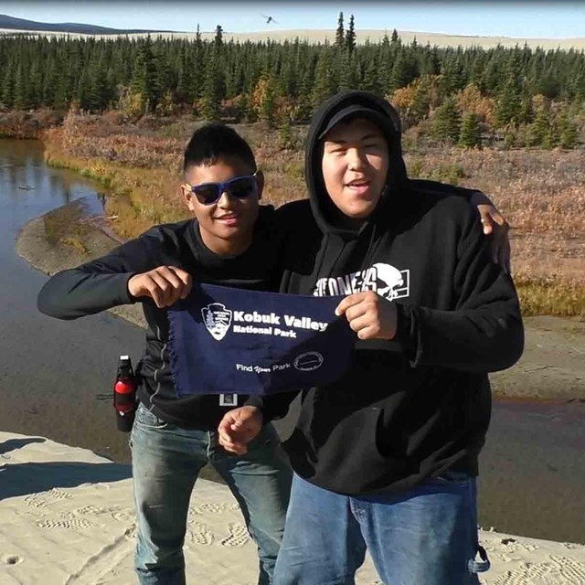 Two Alaska Native boys hold a banner for Kobuk Valley in their video postcard.