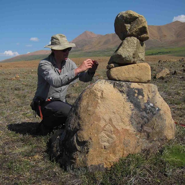 An archaeologist photo documents a cairn.