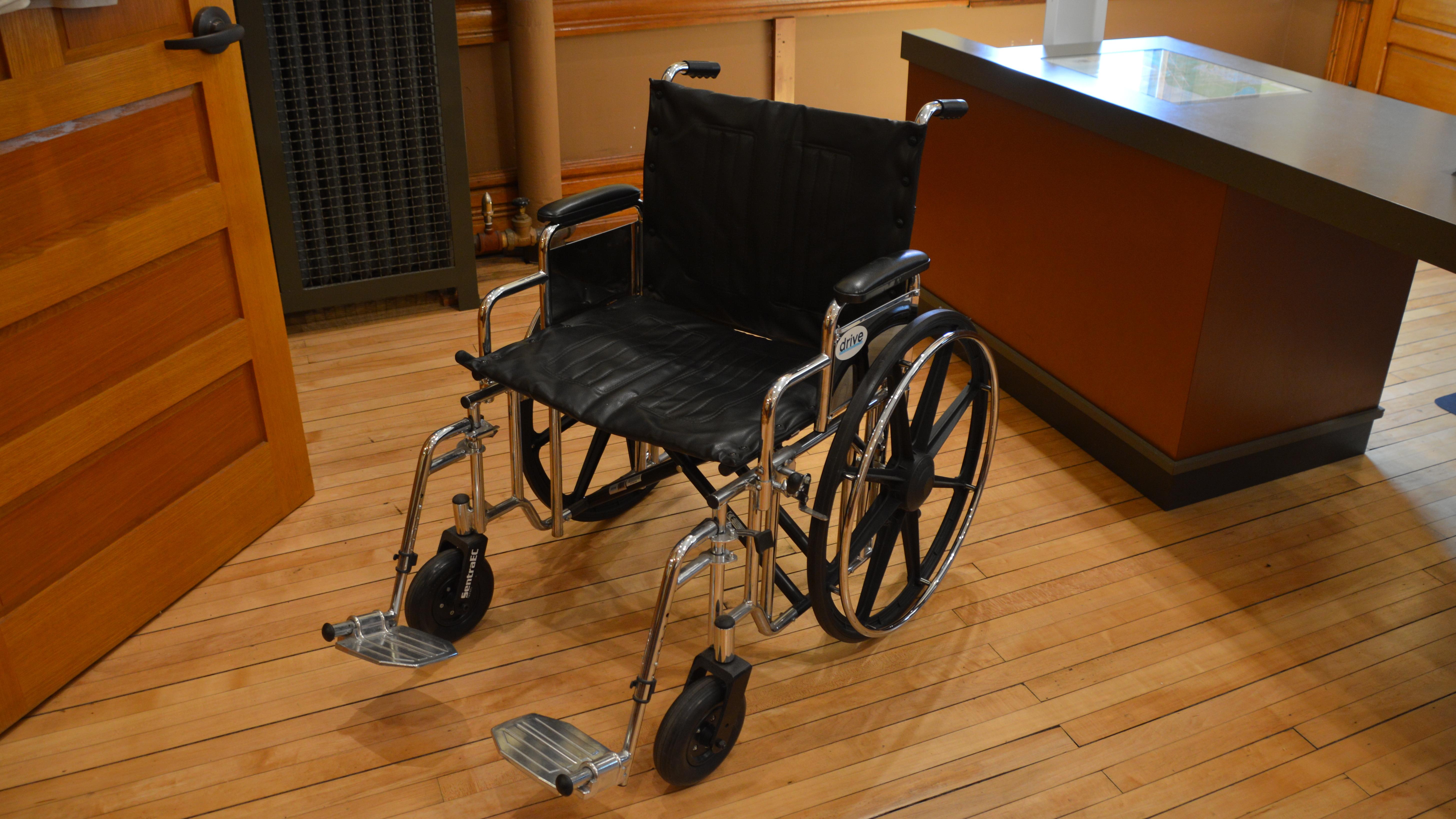 An empty wheelchair in a room with wood floors.