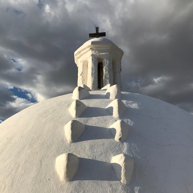 church dome with stormy sky in background, flakes of plaster and cracks showing