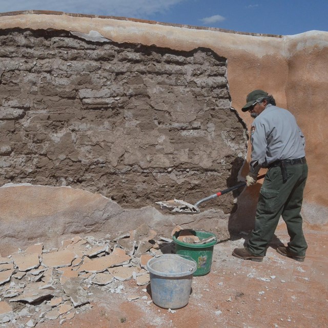 modern ranger applying plaster to adobe wall