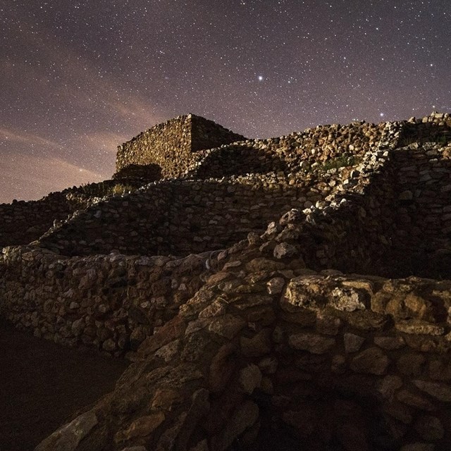 night sky illuminating outline of pueblo structure