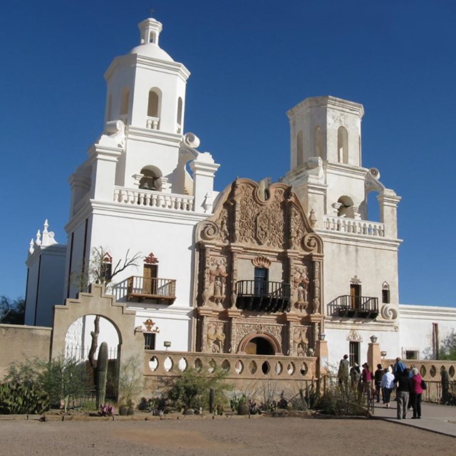 white and tan chapel with group of people walking through front door