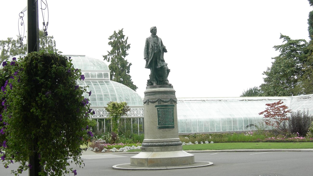 Image of large stature and pedestal in garden area. 