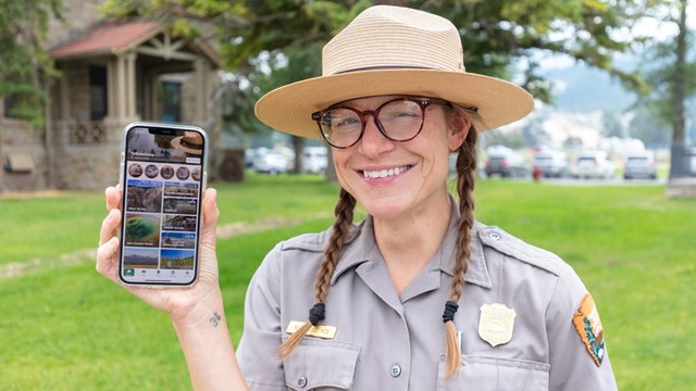 Ranger holding a phone displaying the NPS App
