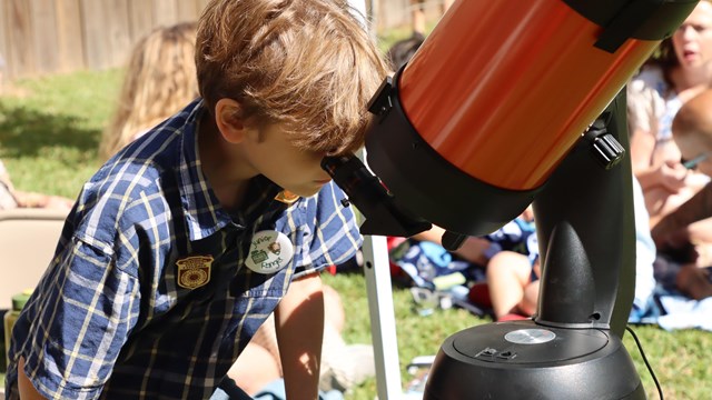 Child looks down into a large solar viewing scope.