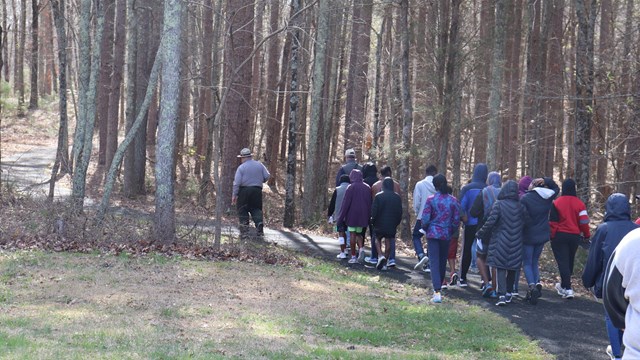 Park Ranger leads visitors on a paved path toward the battlefield.
