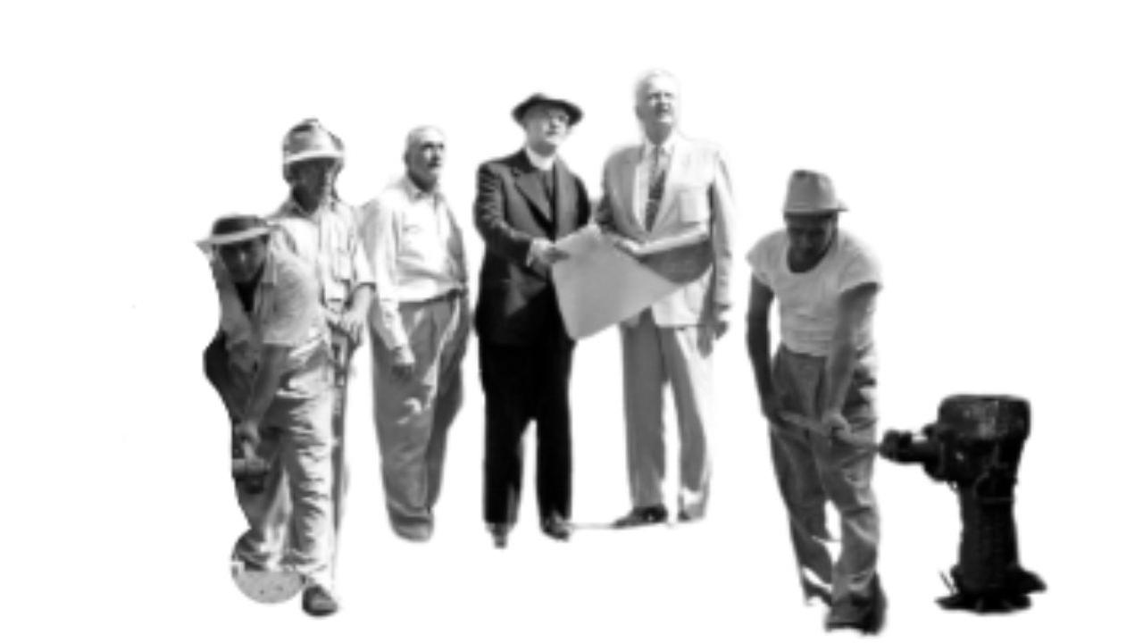 Black and white photo of men looking at a blueprint in a construction site