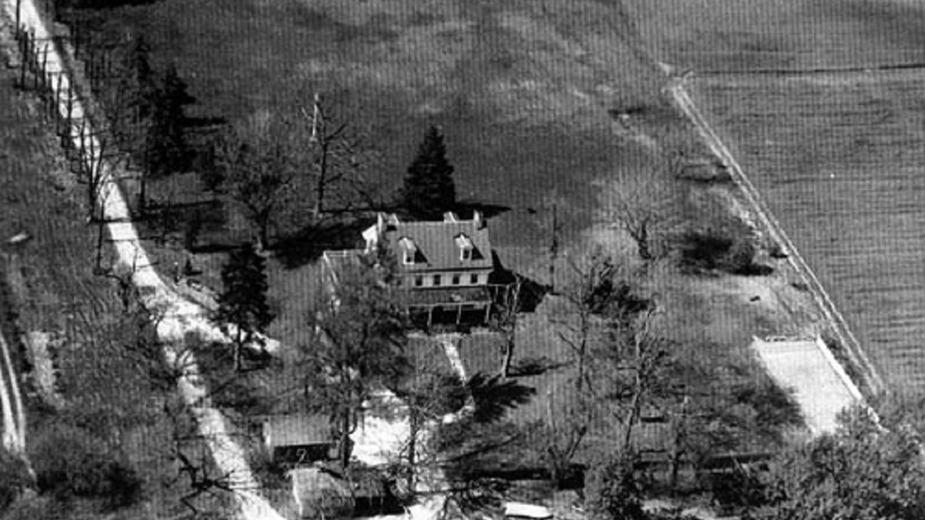 Black and white aerial photo of house in the country. Photo: by Robert M. Hunt, CC BY-SA 3.0,