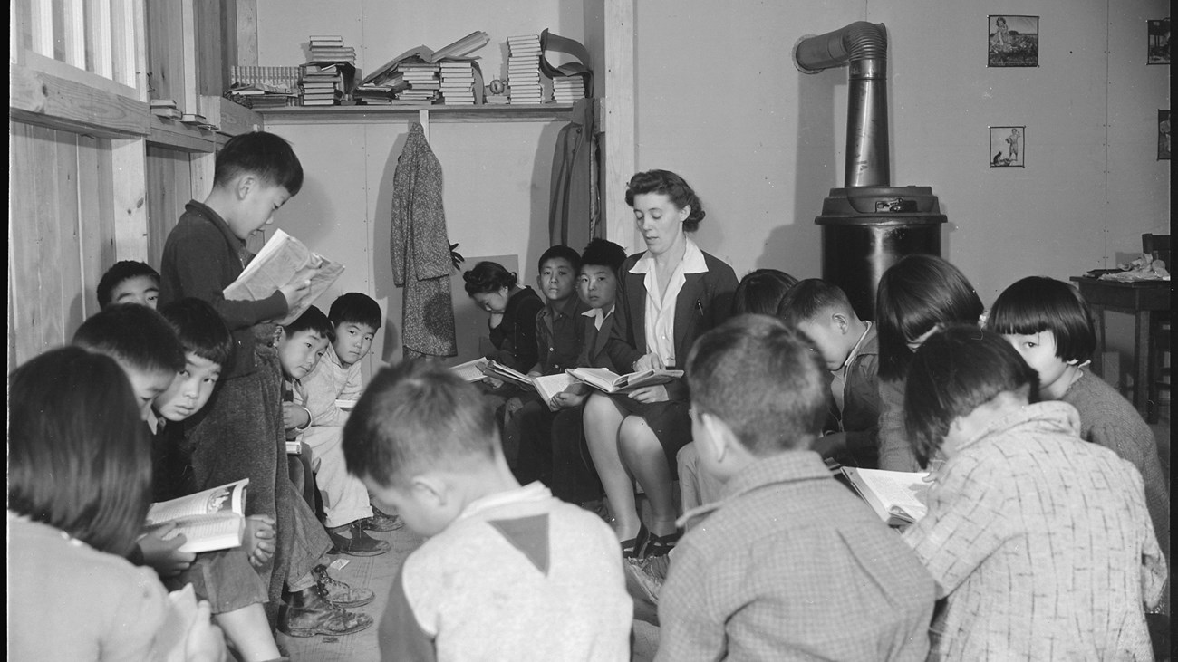 Young Japanese American students gather in a circle to read with their teacher