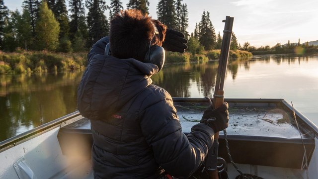 a hunter holds a rifle while riding in a boat