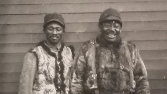 Black and white photo of two Black whalers standing and posing for the camera. 