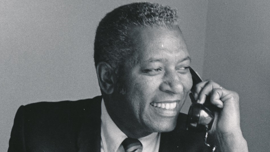 Black and white portrait of Willard Bowman sitting at a desk and talking on the telephone.