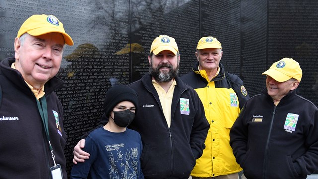 Volunteers pose for a picture in front of the Vietnam Veterans Memorial 