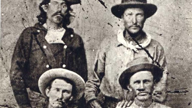 Four men sit for a portrait in western attire.