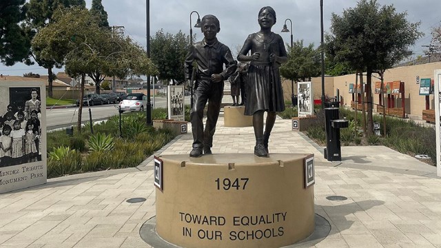 Statue of a young boy and girl walking with books in their hands. 