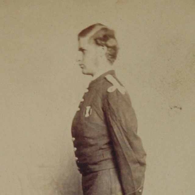 Studio portrait of young man in Civil War uniform standing in profile