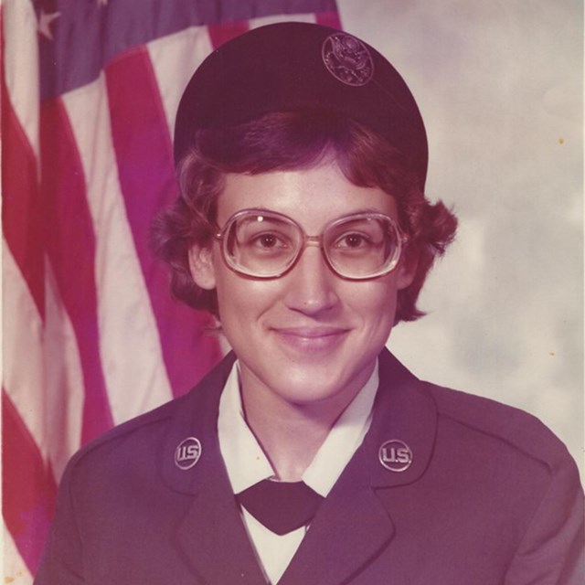 Photo of Lori in uniform in front of an American Flag. Photo courtesy Lori