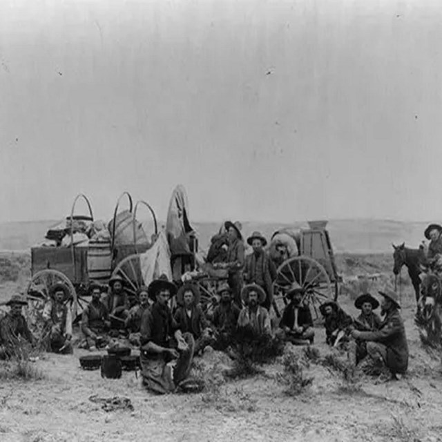 large group of men relaxing at a camp in a wild field