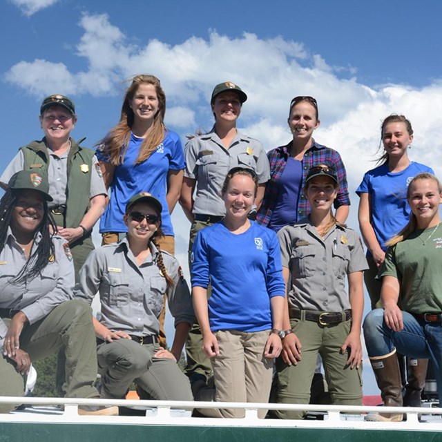 A group of women fisheries interns and NPS staff in a group photo against a blue sky