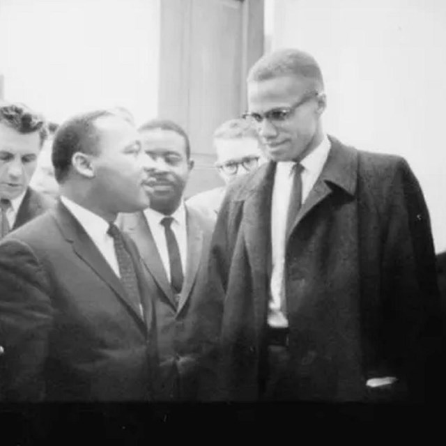 Malcolm X and Martin Luther King Jr. standing in a crowd