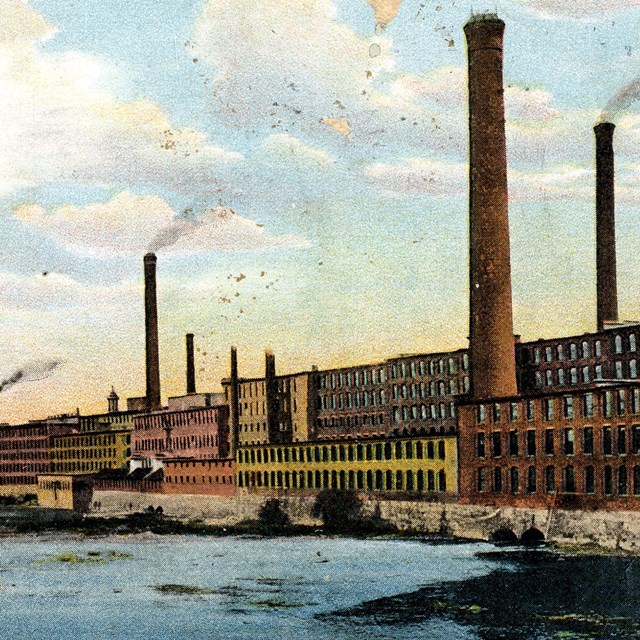Postcard image of mill buildings along a river. 