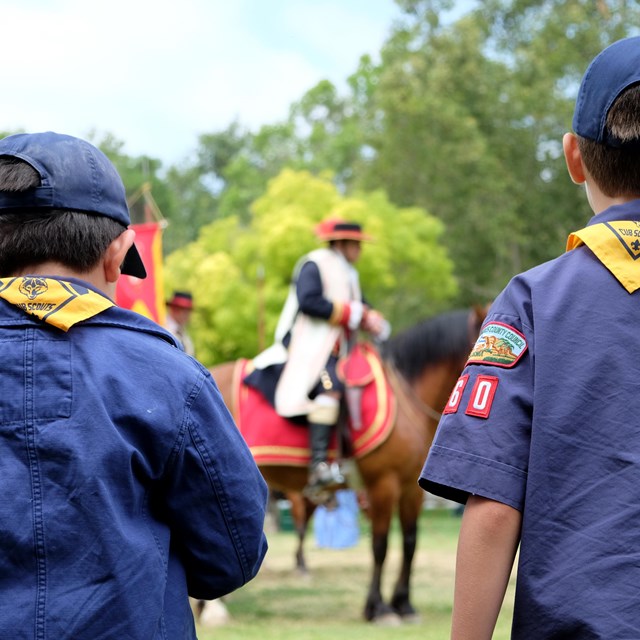 Cub Scouts looking at a living historian portraying a Spanish explorer on horseback