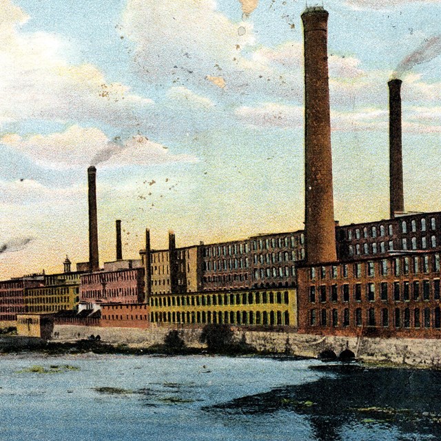 Postcard image of mill buildings along a river. 