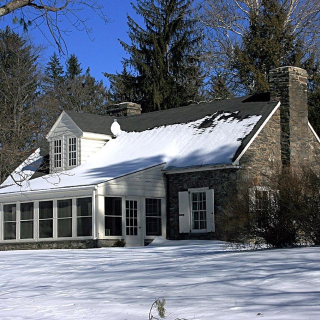 Photo of small snow-covered stone cabin. 