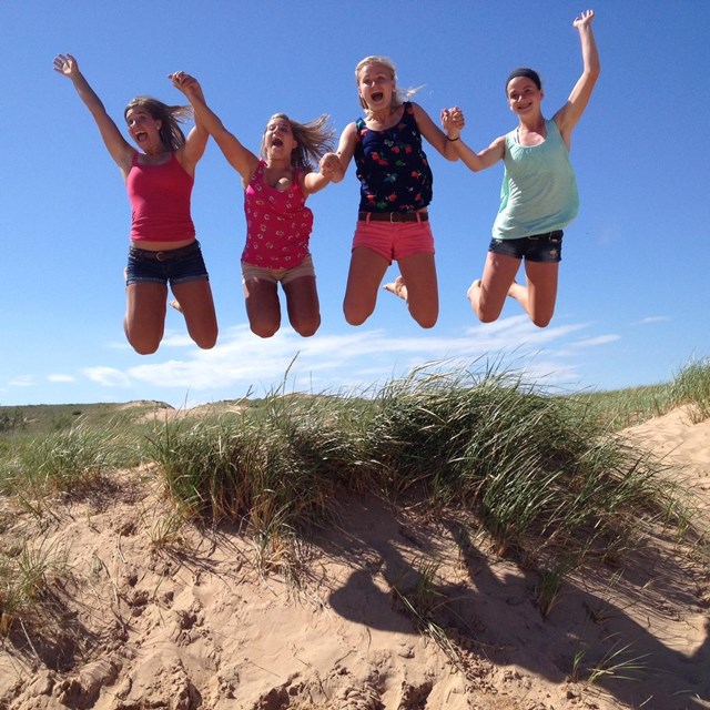 Four kids jumping on a sand dune