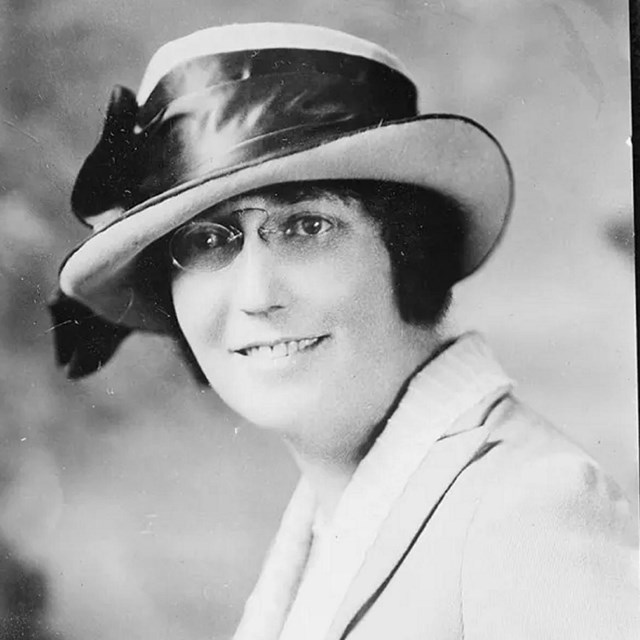 Black and white photo of a white woman in a hat smiling at  camera