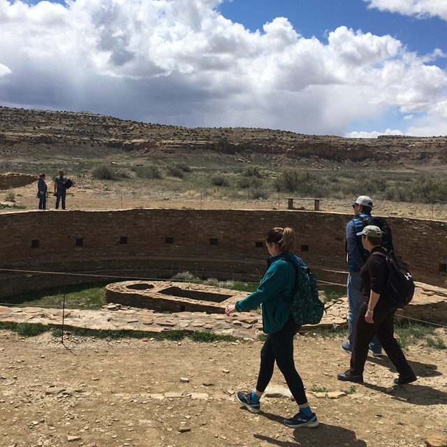 People walk alongside a kiva